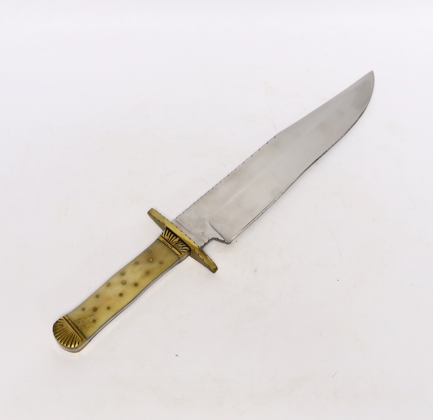 A Bowie knife with clip point blade, unsharpened false edge and decorative filework, marked made in Sheffield England, with bone grip, decorated with brass pins, brass guard and pommel, blade 25.5cm